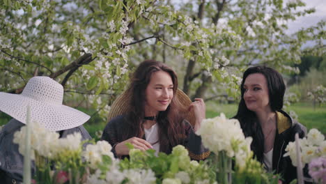 happy-women-are-resting-together-in-garden-lunch-in-blooming-orchard-in-springtime-merry-ladies